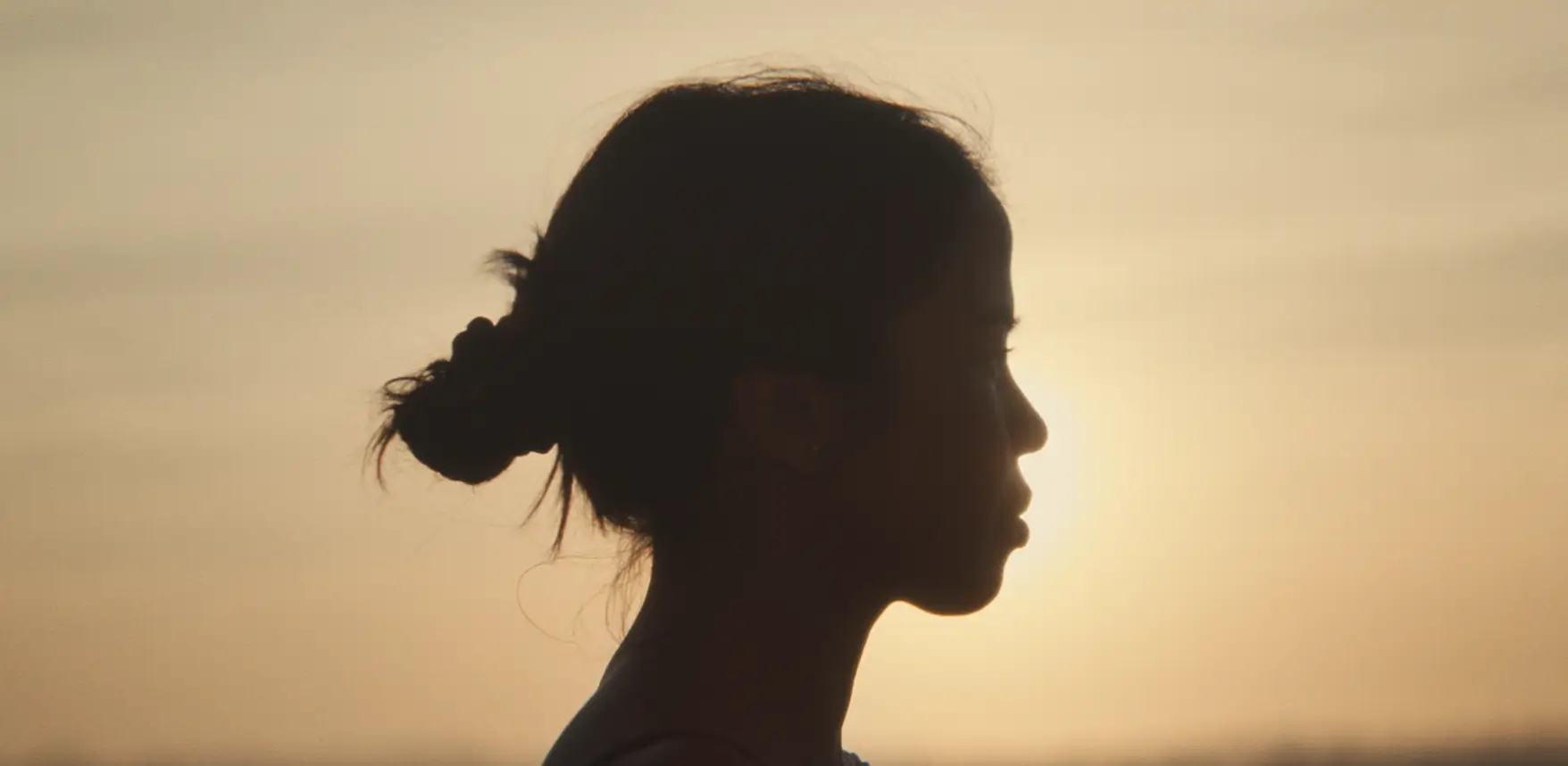 Silhouette of a woman in profile against a sunset sky