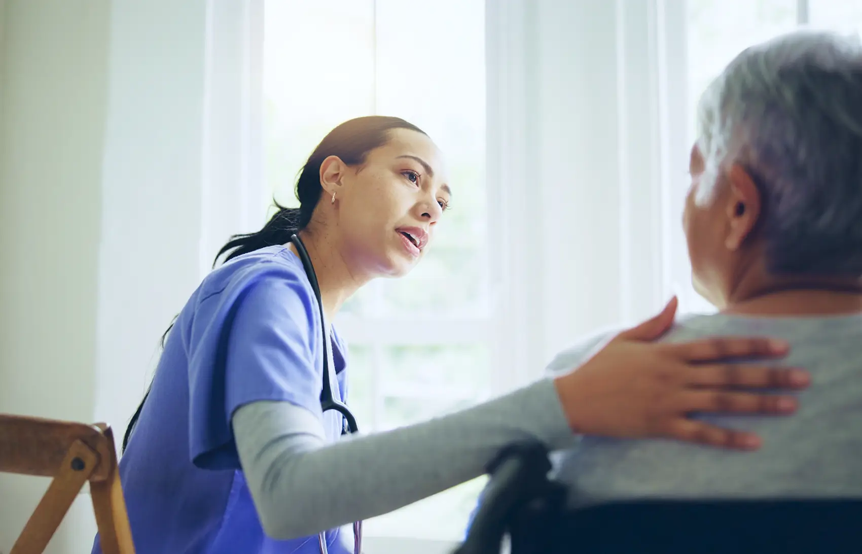 Nurse comforting an elderly person in a wheelchair