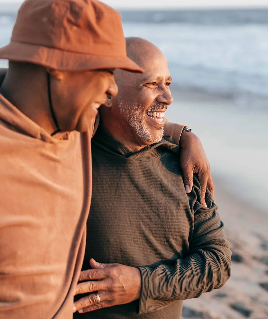 Two men smiling and walking together on a beach