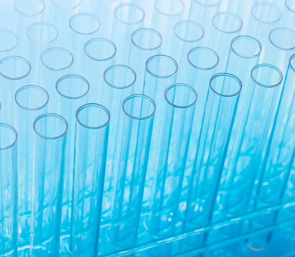 A close-up shot of a rack of empty, clear test tubes, with a blue gradient applied to the lighting.