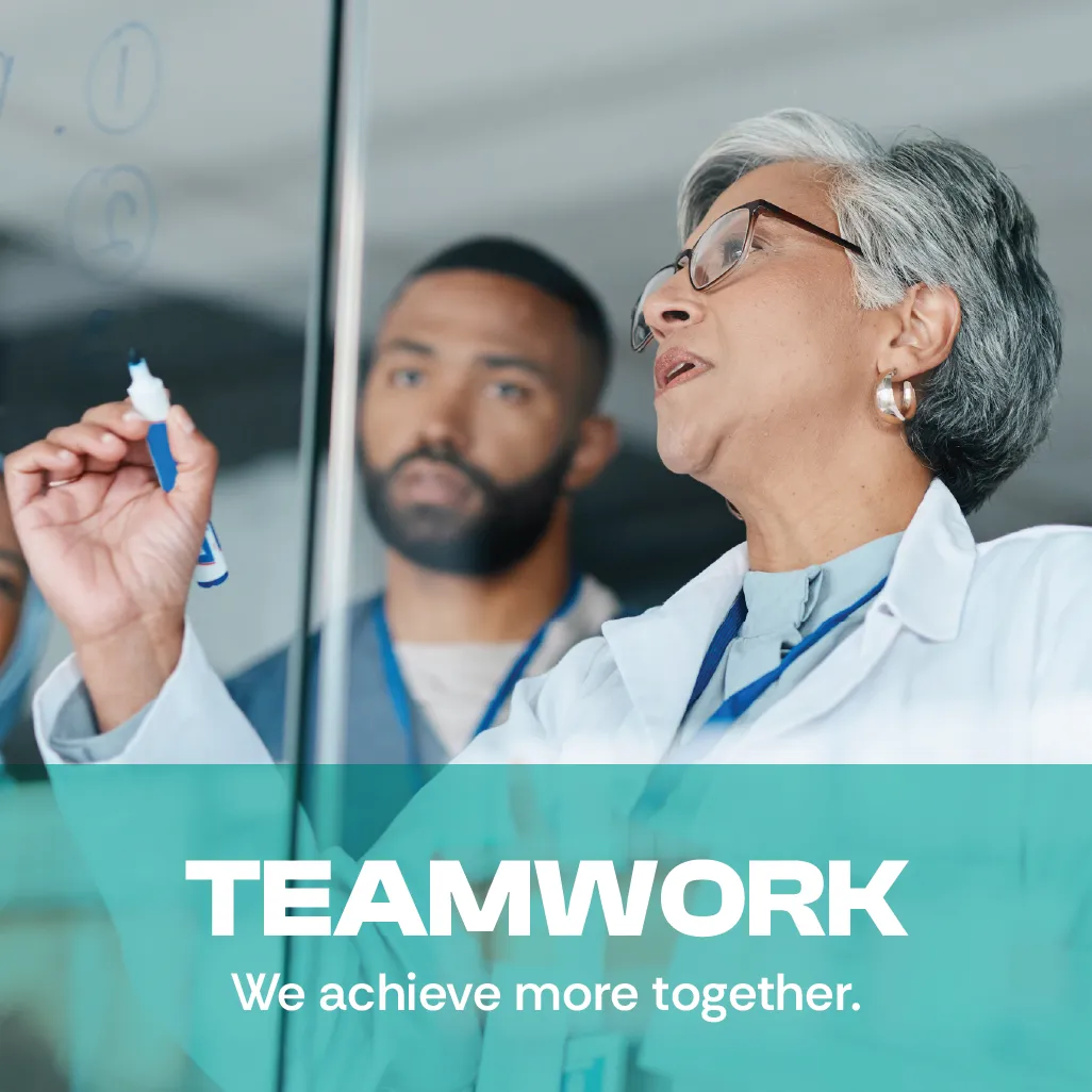 Teamwork. We achieve more together. A photo of a middle-aged female scientist and a young man writing on a writing on a white board.
