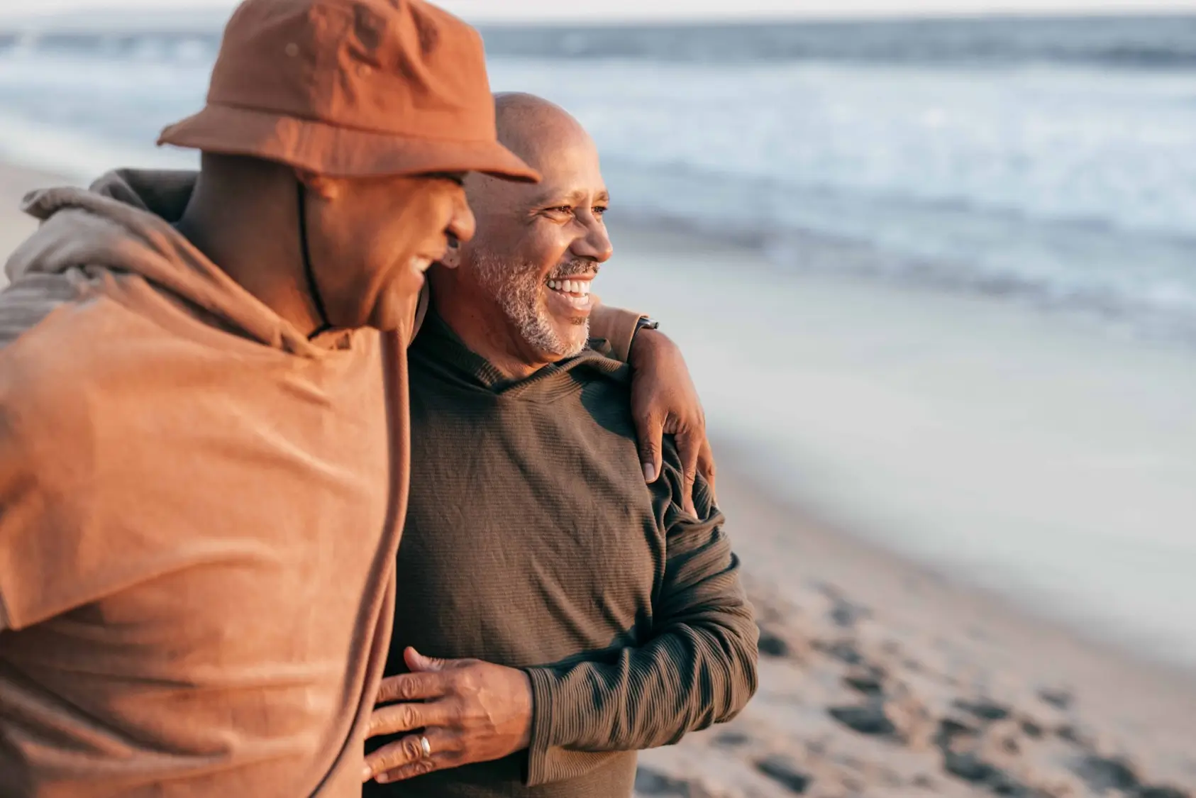 Deux hommes s'embrassant et souriant sur la plage