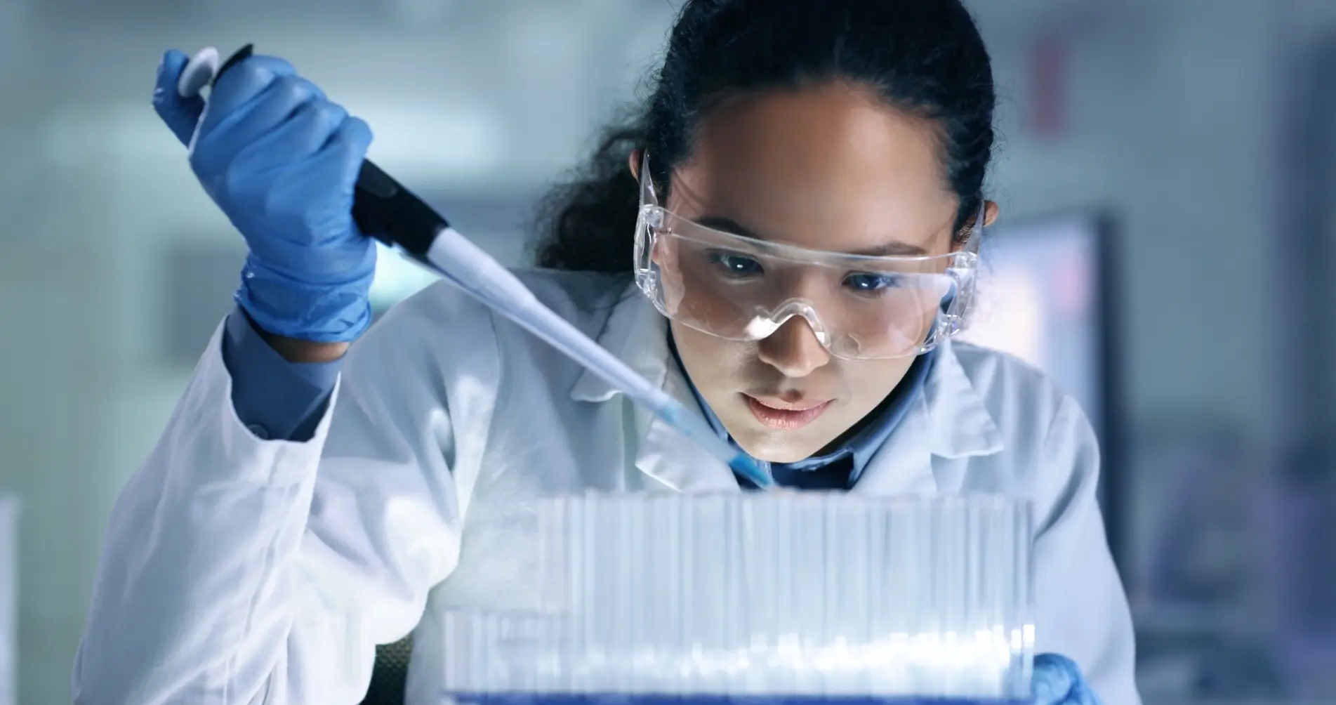 Un scientifique portant des lunettes et des gants utilise une pipette dans un laboratoire.