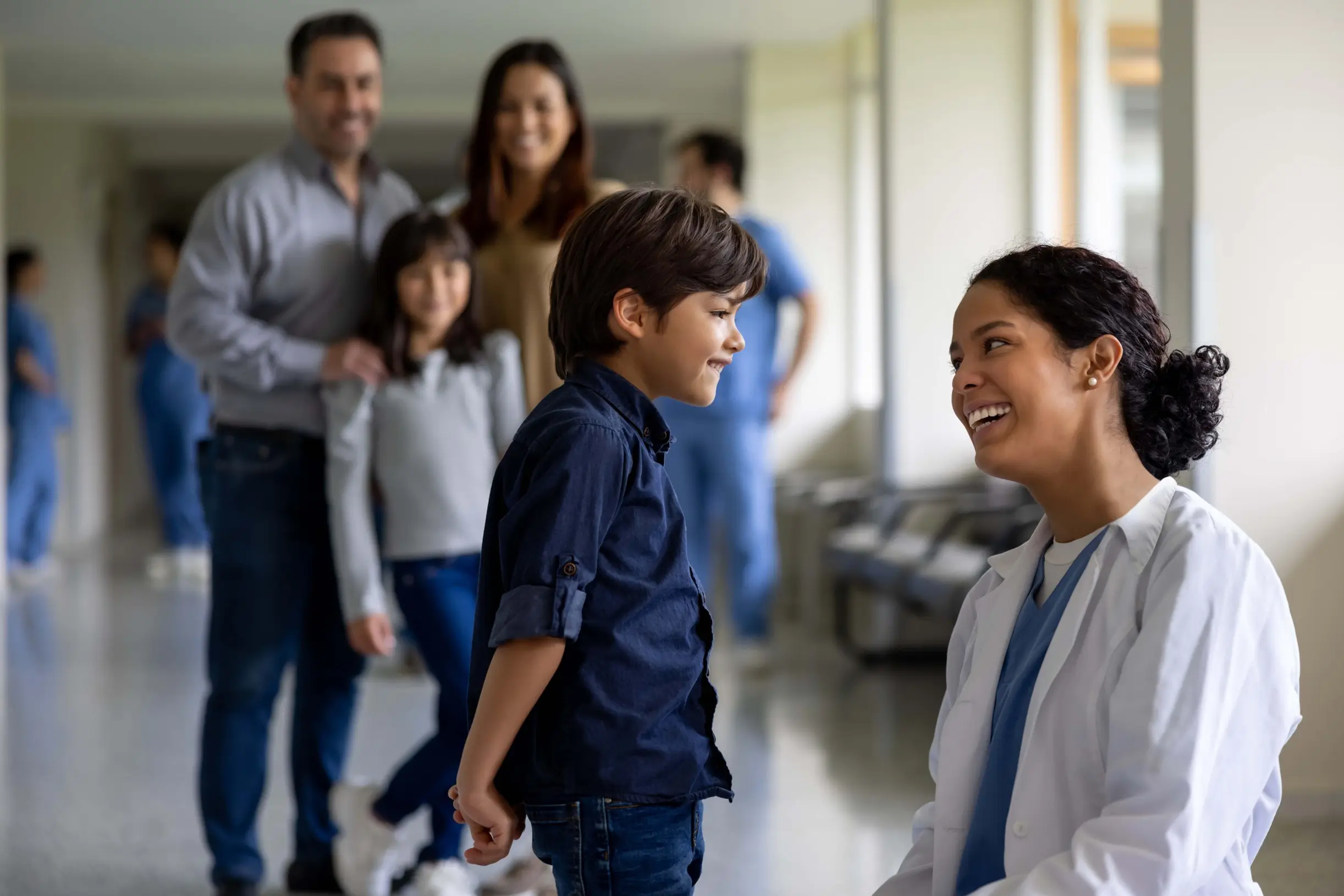 Healthcare professional smiling with a child with family in background