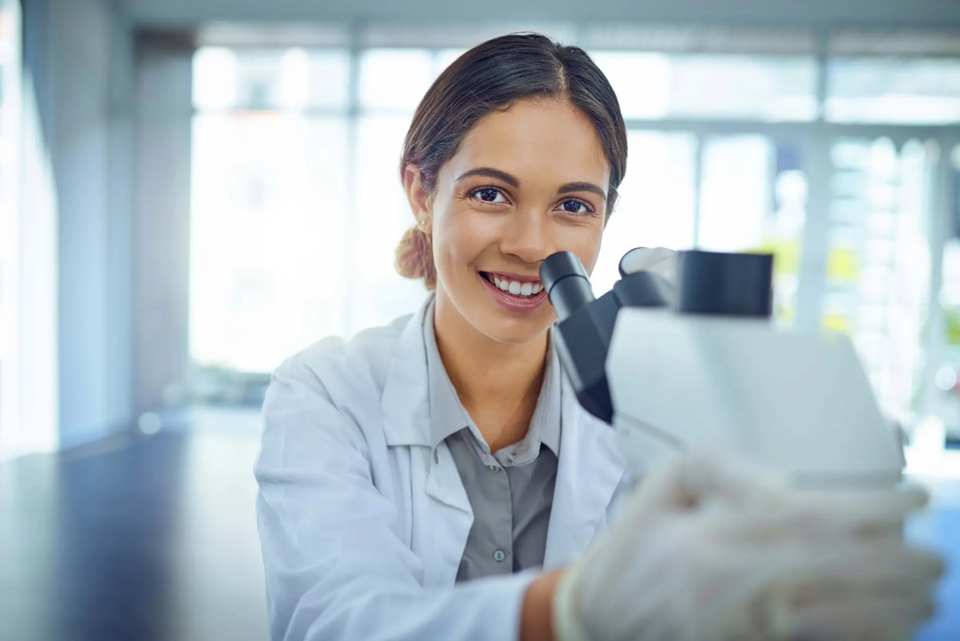 Smiling scientist using a microscope.